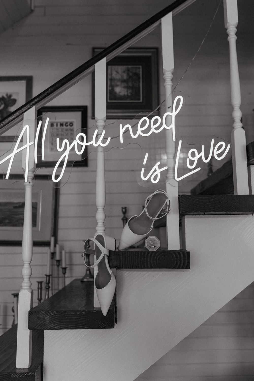 Black and white staircase with white spindles and a love message written in cursive neon text along the wall.