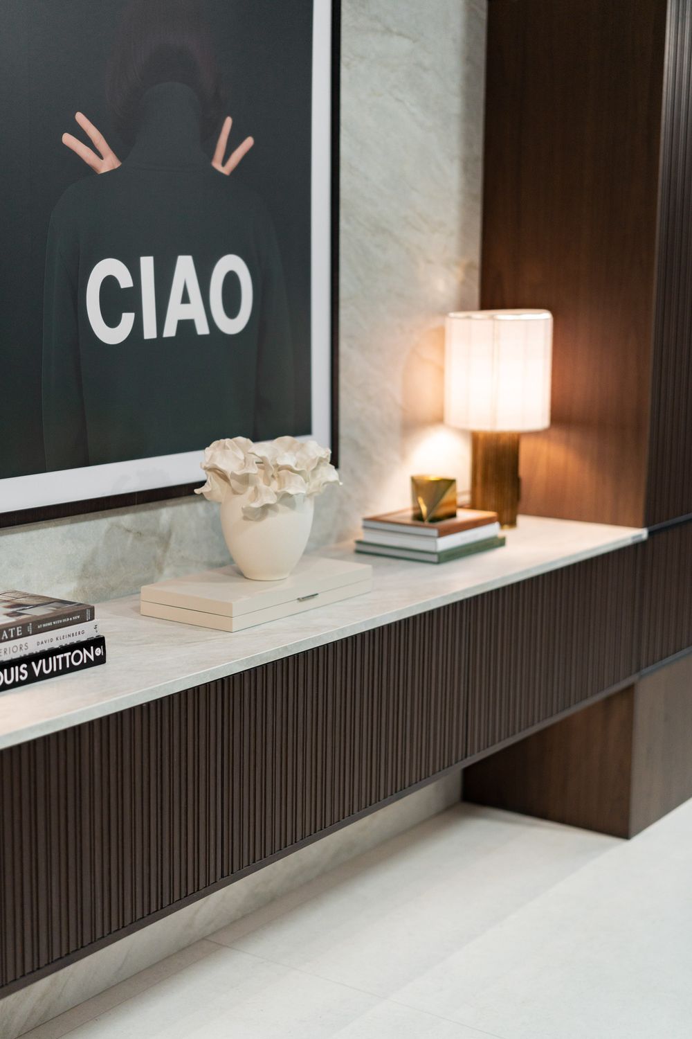 Modern interior design featuring dark shelving with white accents, books, and decorative 'CIAO' text on the wall.