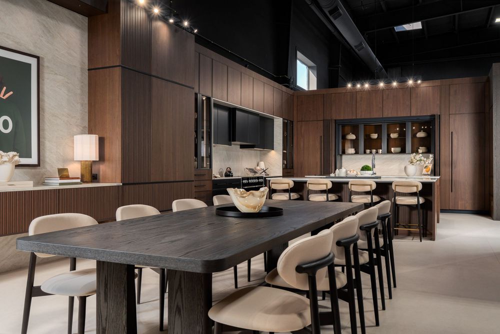 Contemporary dining room with dark wood paneling, long table and upholstered chairs under track lighting.