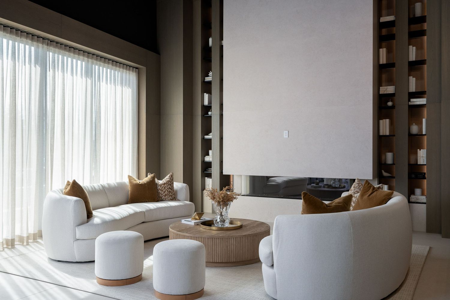Contemporary open-plan lounge area featuring white curved furniture and floor-to-ceiling windows.