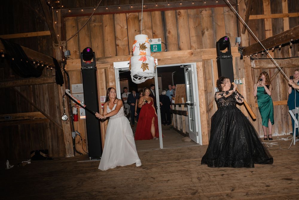 Wedding guests dance and celebrate inside a rustic wooden barn during an evening reception.