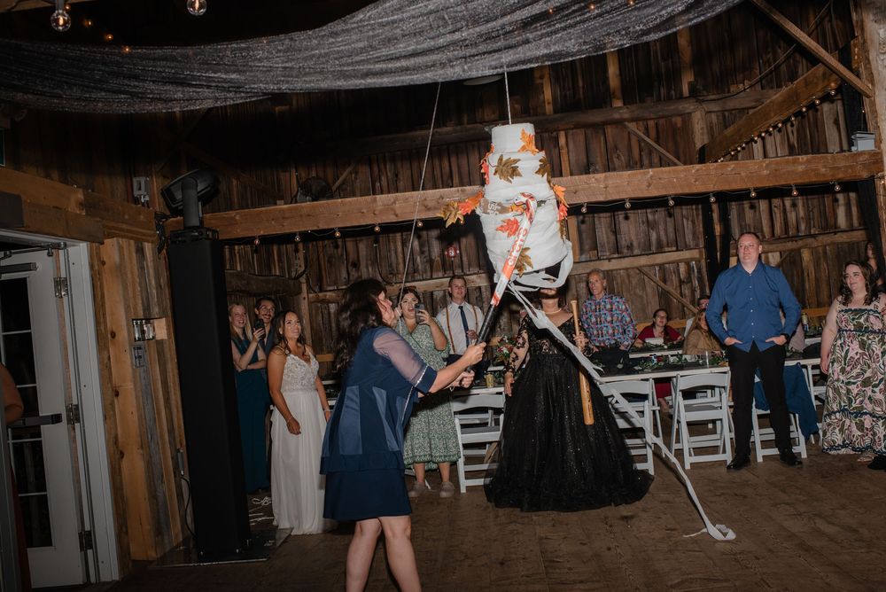 Wedding guests dance and celebrate during a lively reception inside a rustic wooden barn venue.