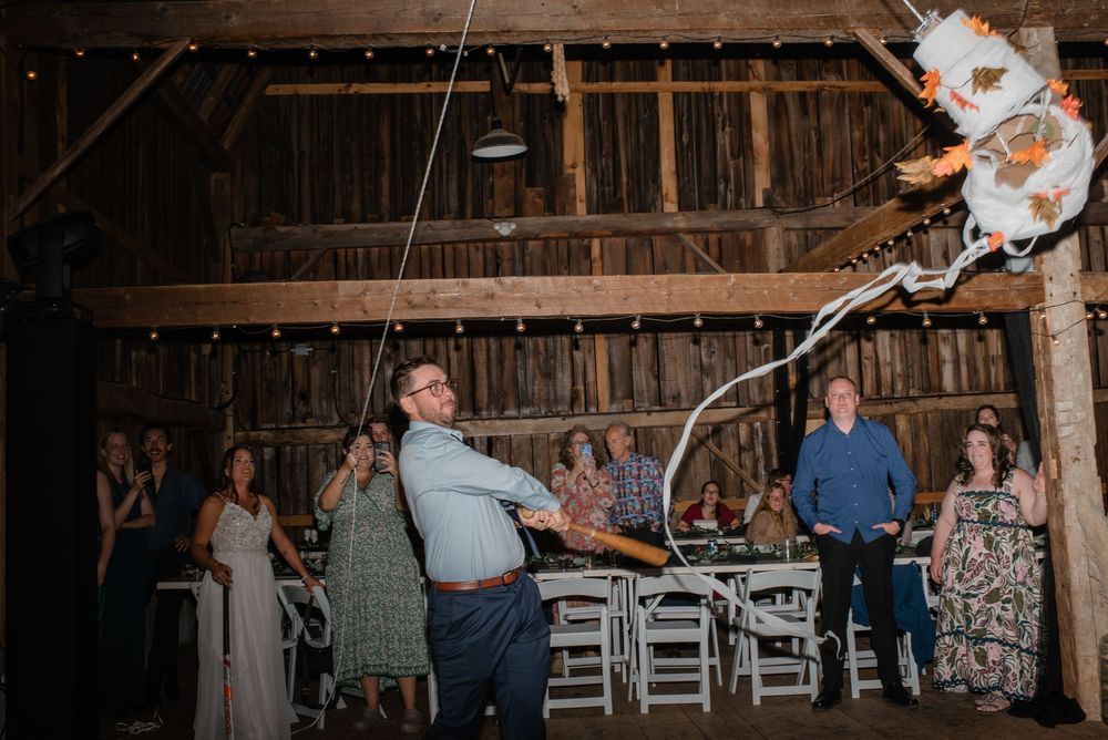 A rustic barn wedding reception features string lights and white folding chairs arranged in rows for the ceremony.
