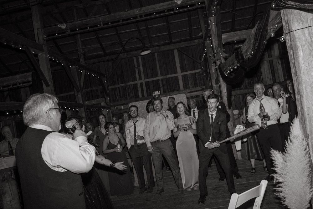 A vintage black and white photograph of people gathered at a dance party in what appears to be a rustic barn setting.