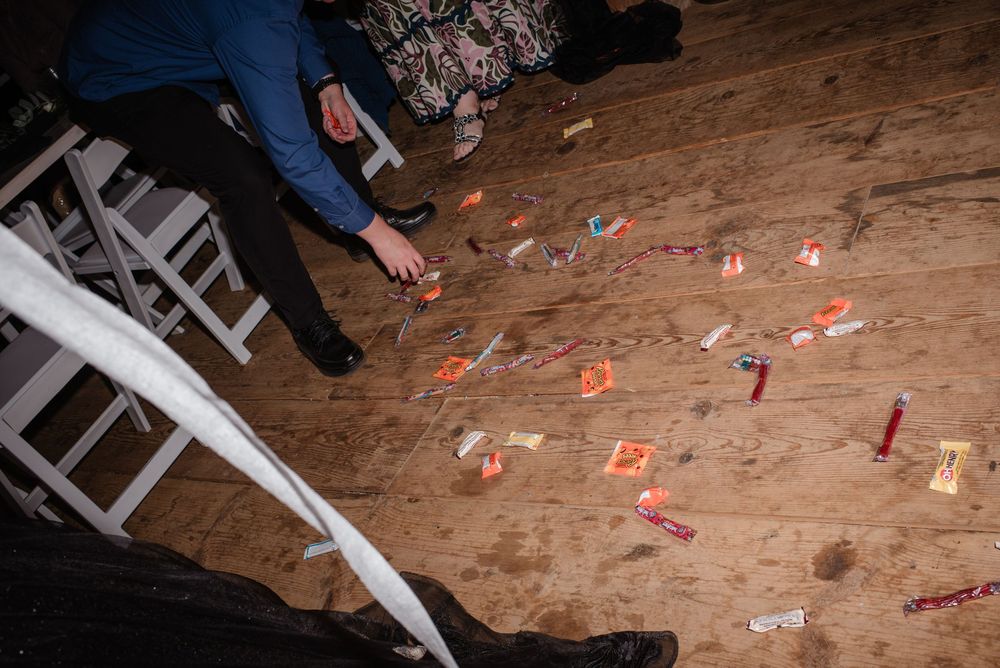 Scattered confetti and decorations cover a wooden barn floor during a wedding celebration.