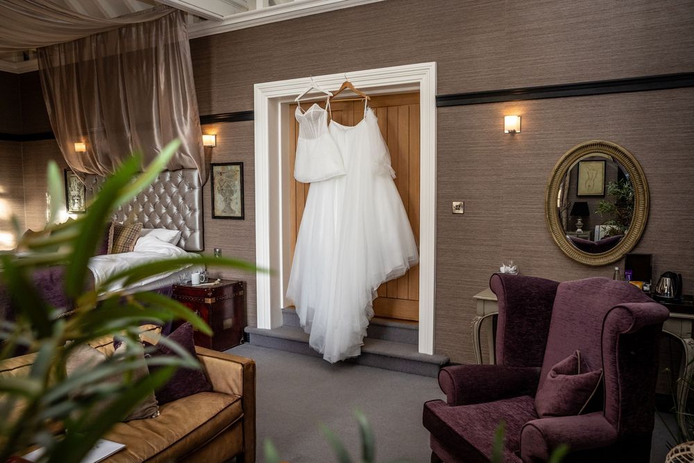 White wedding dress and veil hanging in doorway of elegant hotel bridal suite.