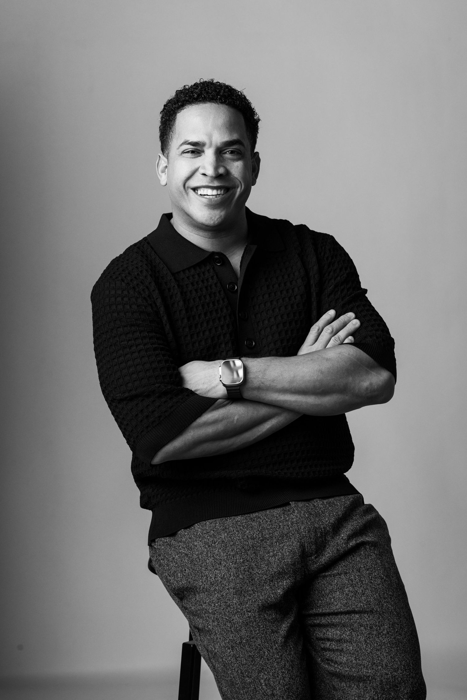 Professional studio portrait in black and white with relaxed confident pose.
