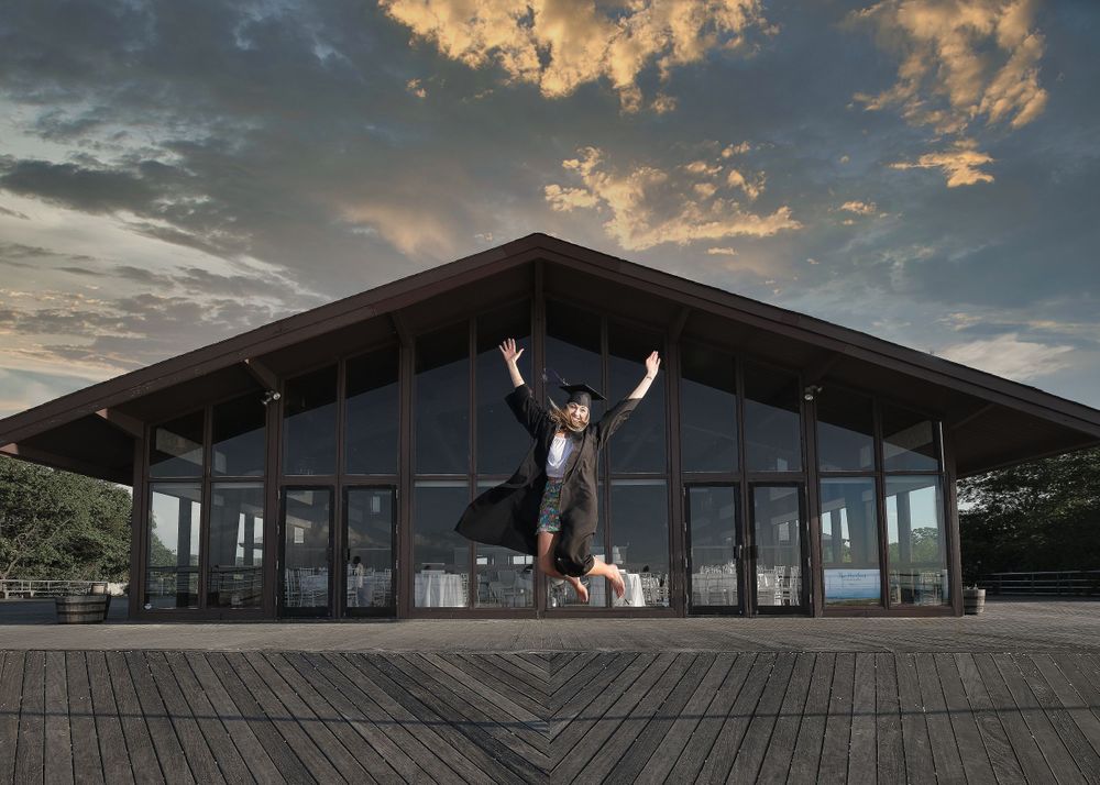 Silhouetted figure jumping in front of modern building during sunset.