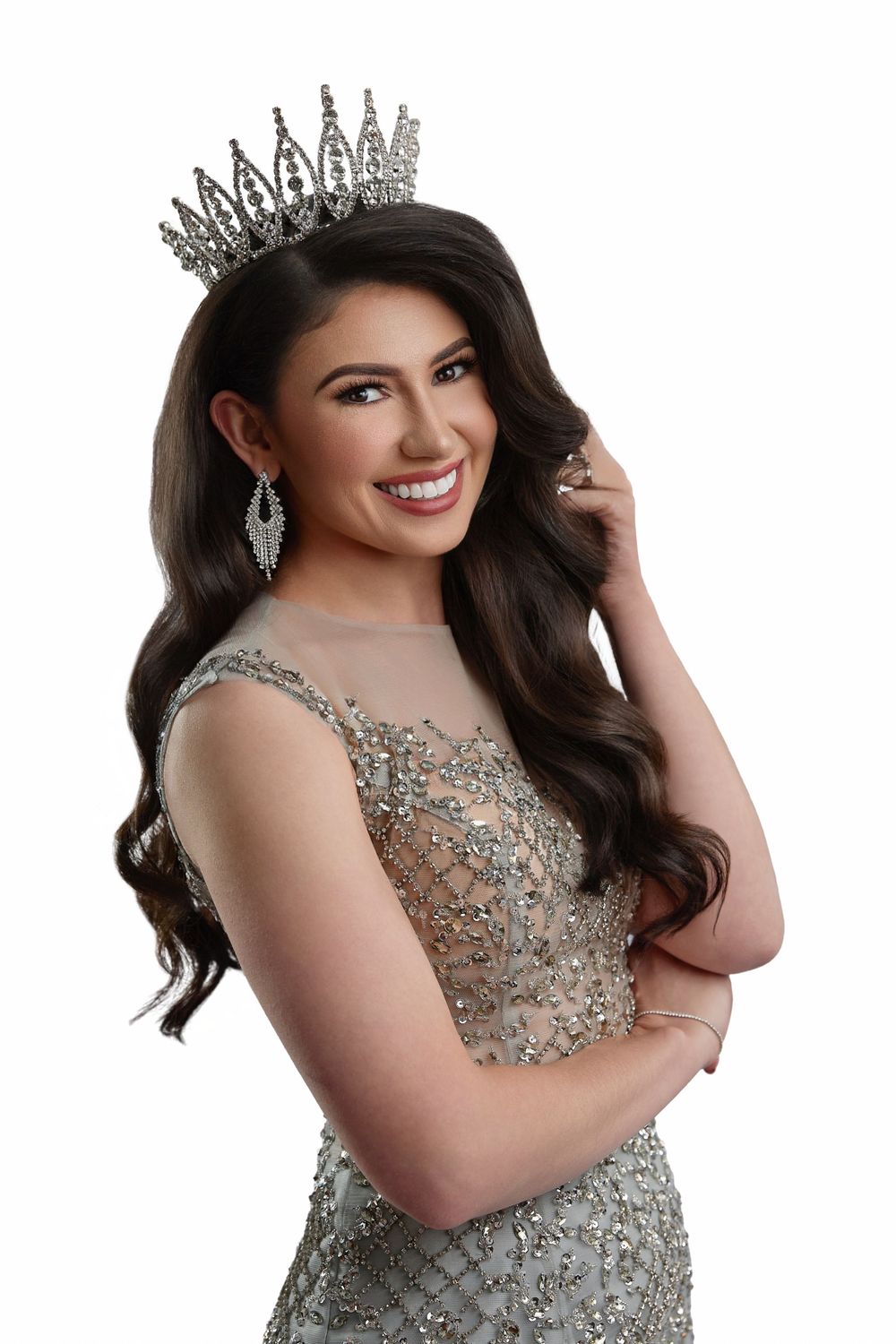 Woman in a sparkling silver evening gown with beaded embellishments poses elegantly in a glamorous photoshoot.