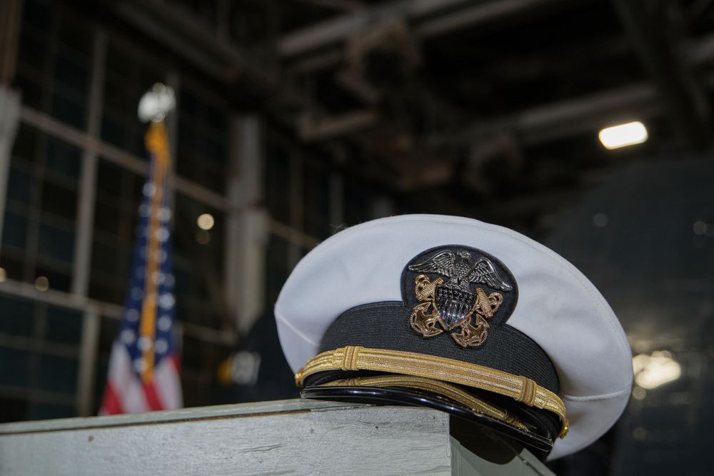 Naval officer's white dress cap with gold insignia displayed on podium.