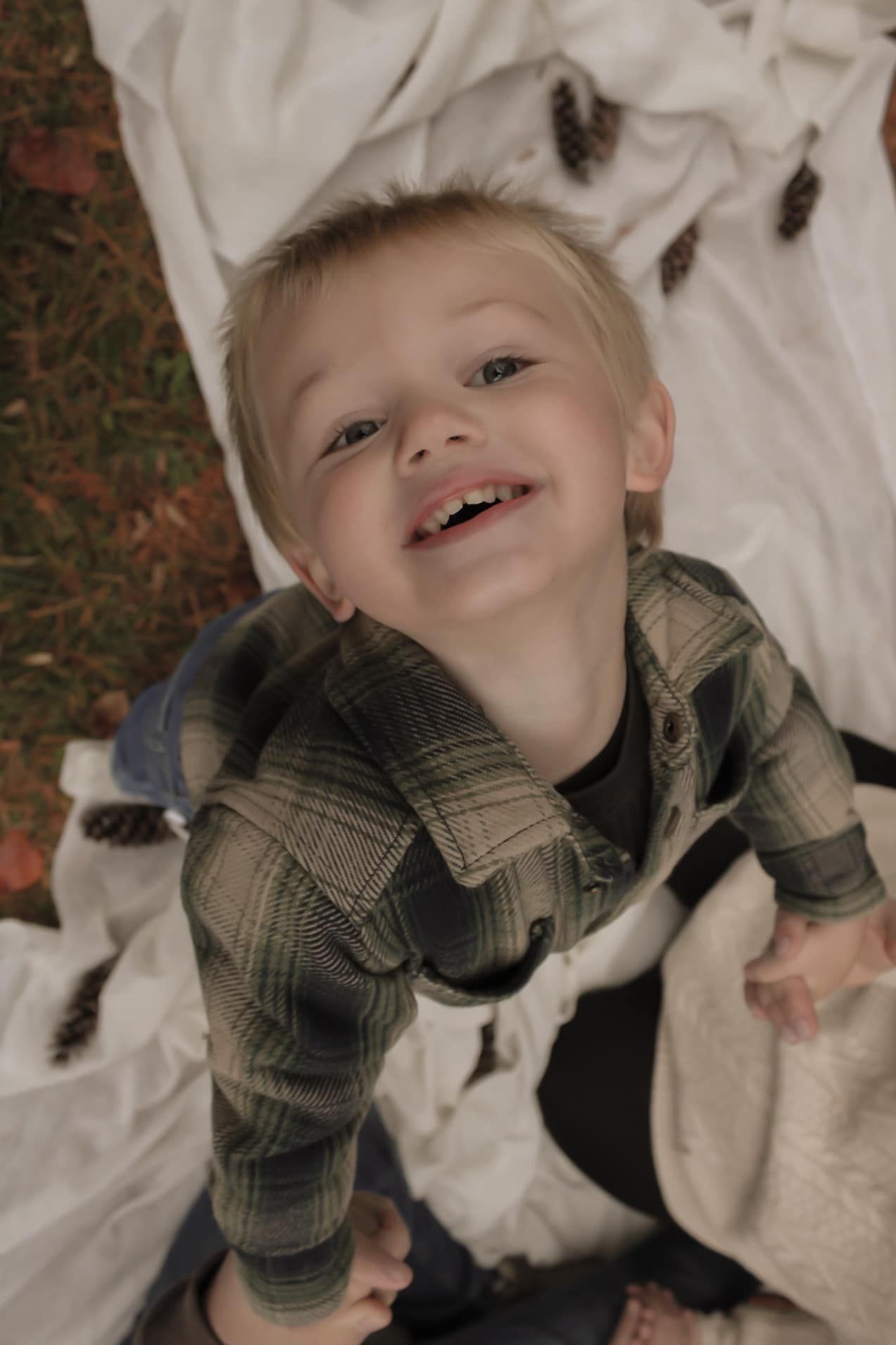 A series of playful expressions captured on a blanket showing pure joy and laughter while wearing a plaid shirt.