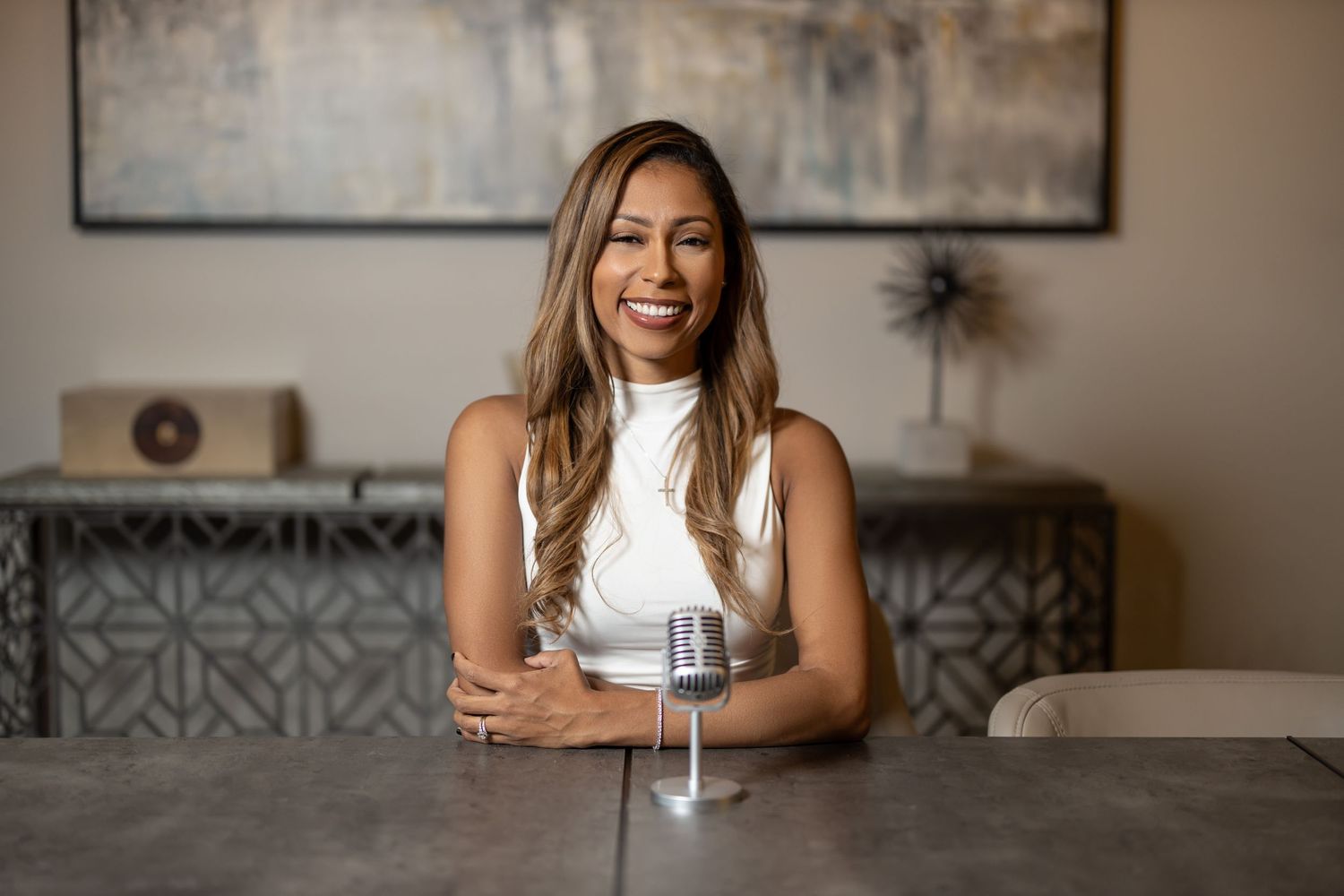 Cheerful business professional seated at table with glass of water in modern office setting.
