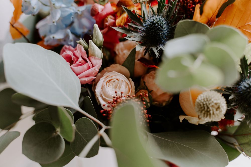 Close up of flowers in a bride’s bouquet. Thistle, eucalyptus and roses.