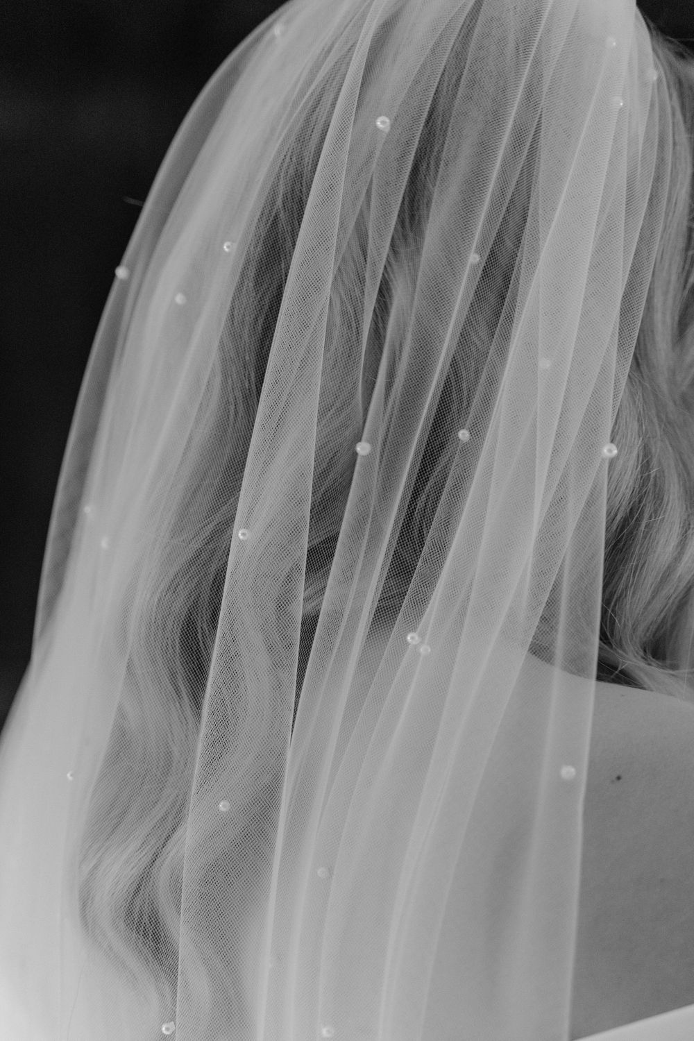 A close up of a bride’s veil which has lots of pearl sewn onto it.
