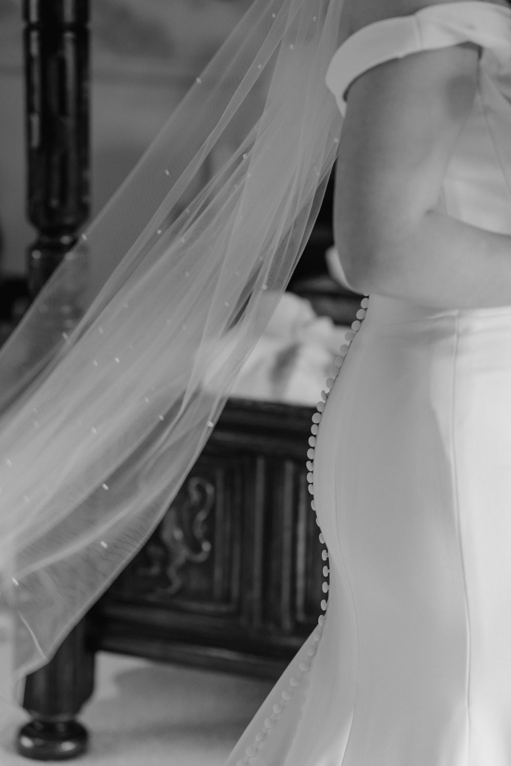 A close up of the bride’s veil and buttons down the back of her dress.