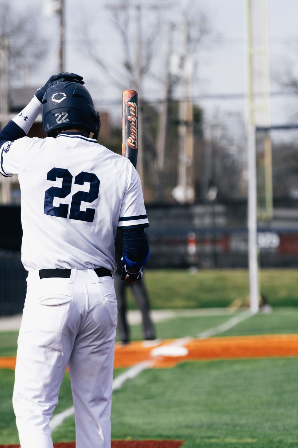 Baseball player in white uniform with number 22 stands ready at bat.