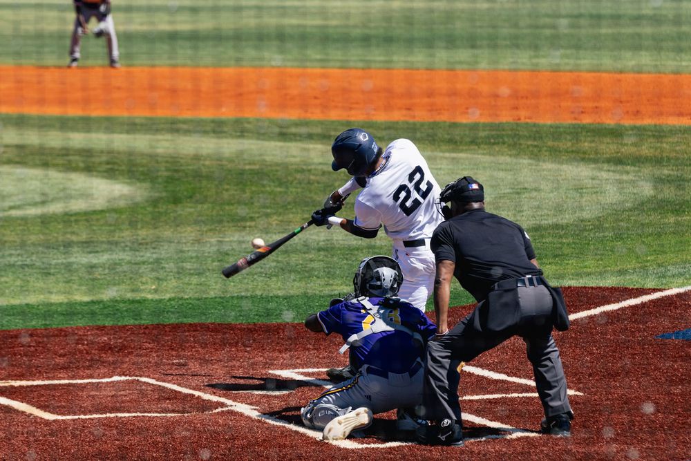 Baseball player slides into home plate as catcher attempts to make the tag during intense game action.