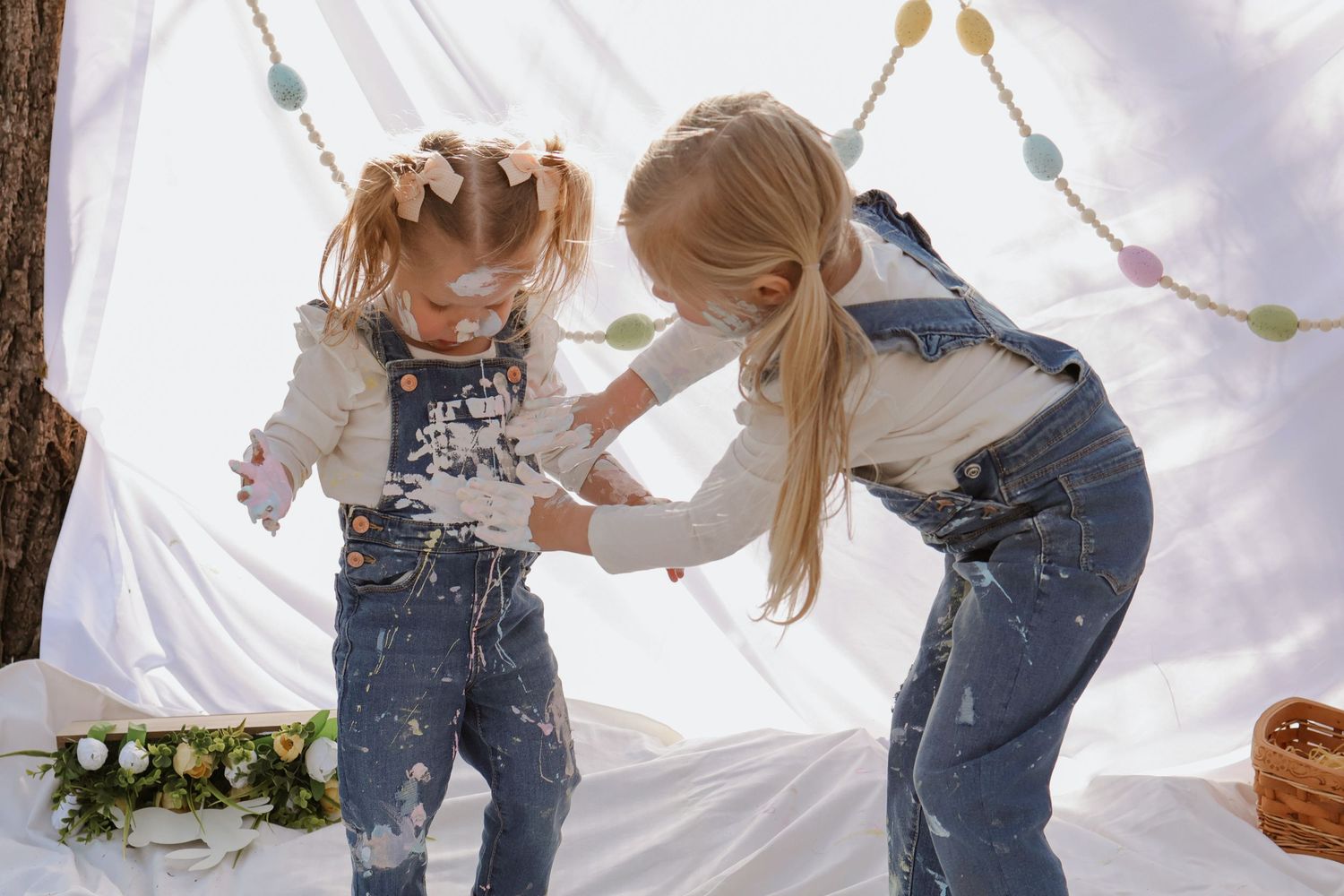 Children playing with artistic elements against a white backdrop.