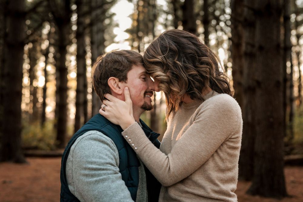 An intimate moment captured between a couple in a forest setting at sunset.