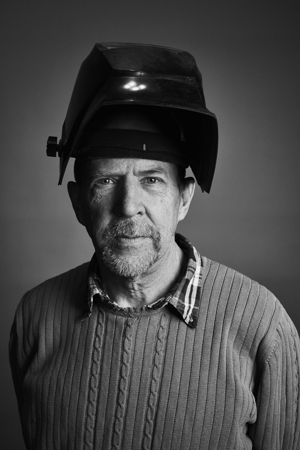 Black and white portrait series showing someone wearing a baseball cap and cable knit sweater with changing expressions.