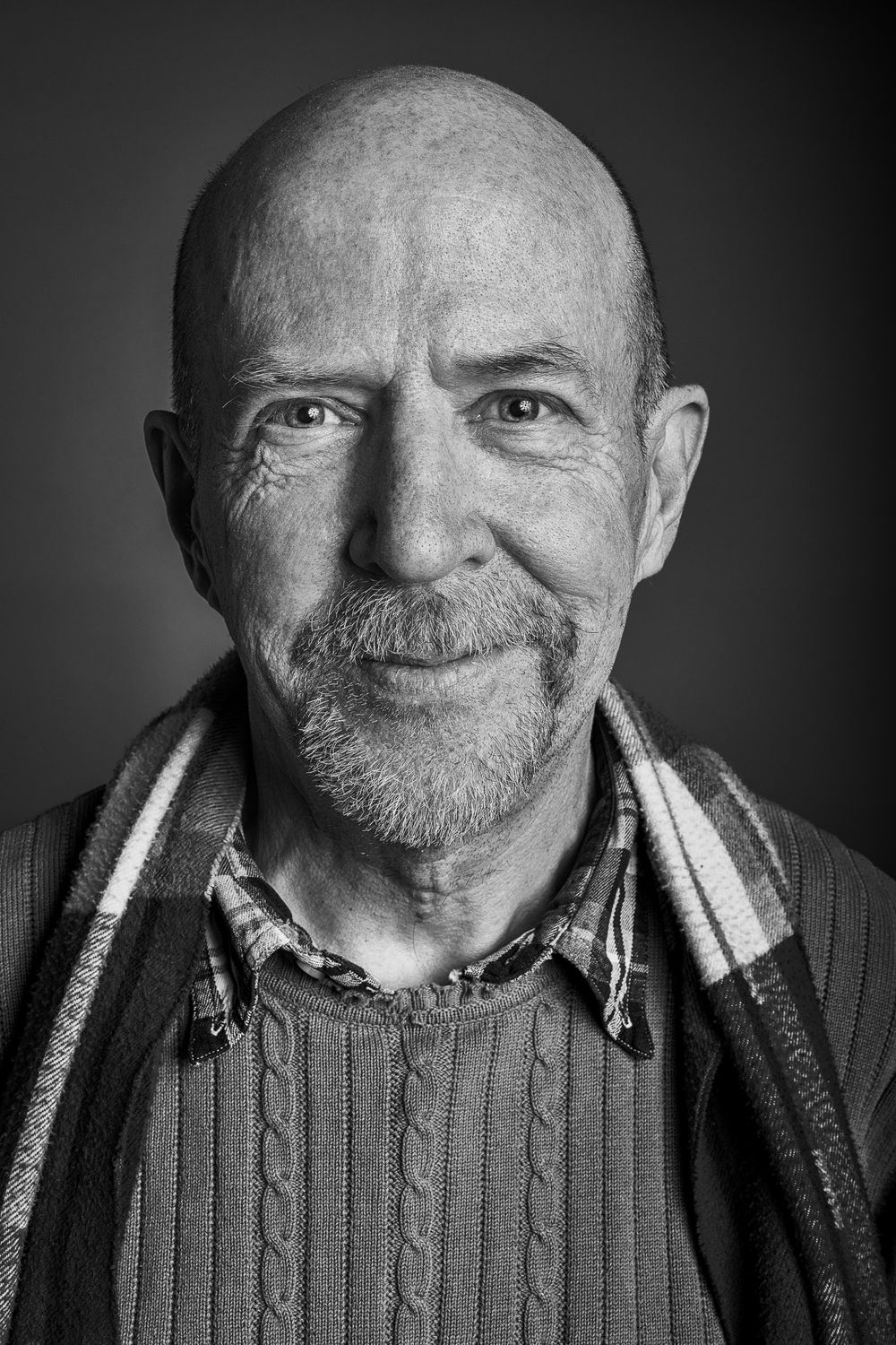 Black and white portrait series showing a person smiling and wearing a knit sweater in varying close-up shots.