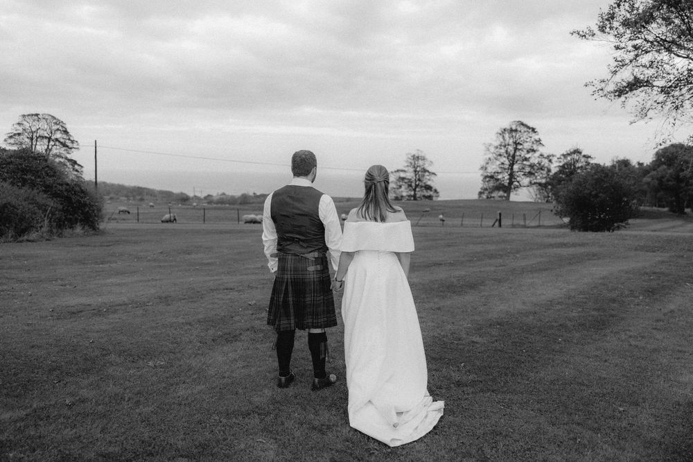A series of black and white photos showing a couple walking and sitting together in an open field landscape.