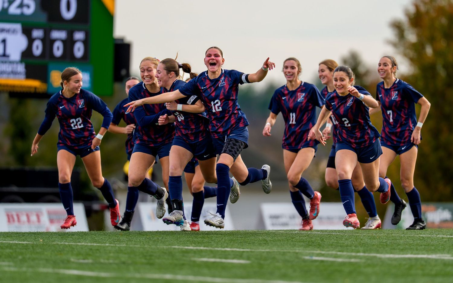 Central Bucks East Girls high school soccer team celebrating goal, players running and smiling on field, PIAA Champions 2025
