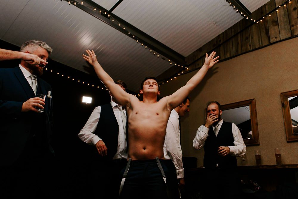 Wedding guests dance and celebrate on a dimly lit dance floor decorated with string lights at a reception.