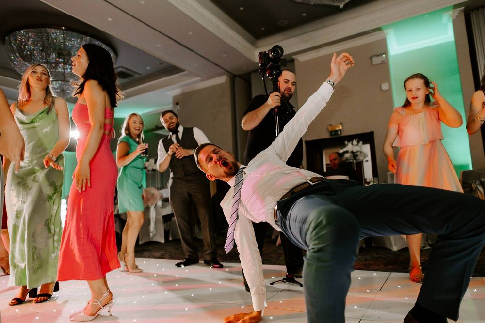 Group of people dancing and having fun at a social dance event with colorful lighting and energetic atmosphere.