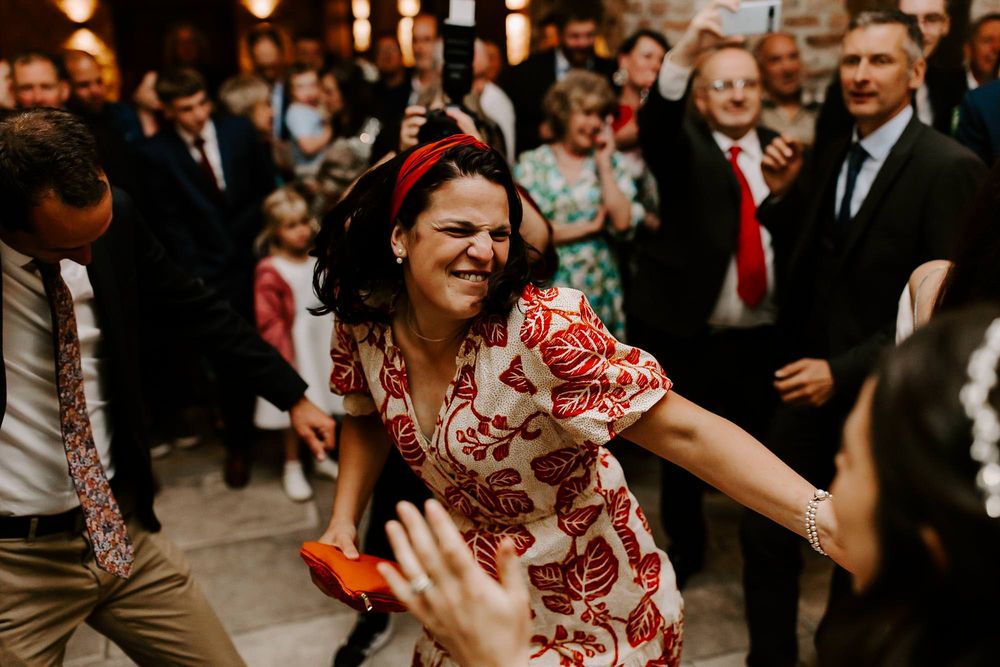 Guests dance and celebrate at a lively wedding reception with warm lighting and festive atmosphere.