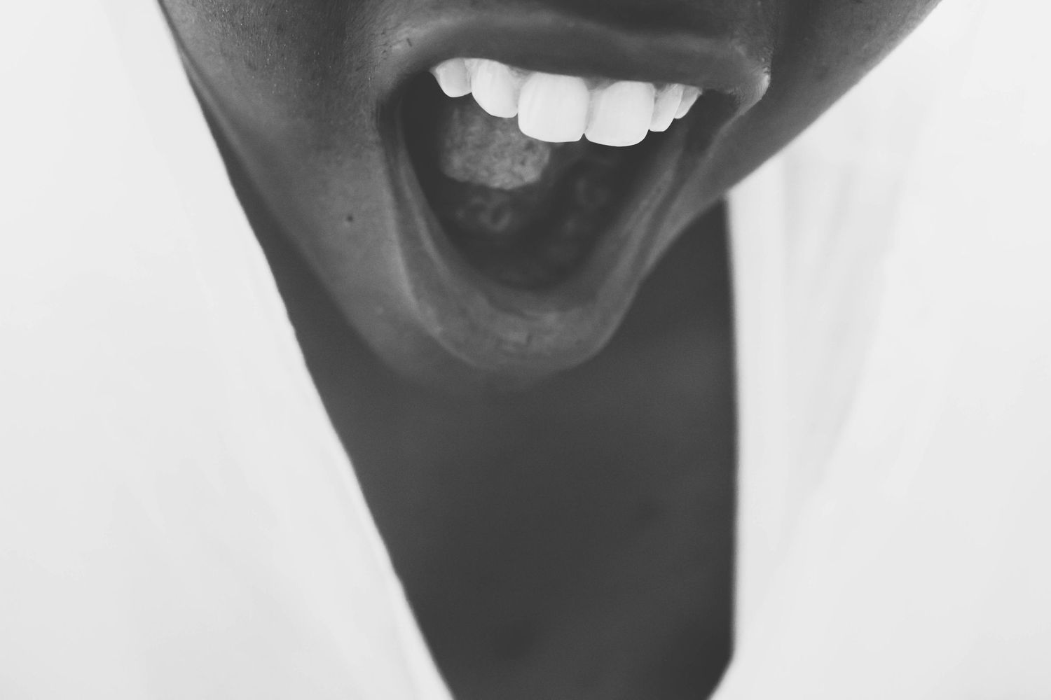 Four black and white close-up photos showing different facial expressions and mouth positions in sequence.