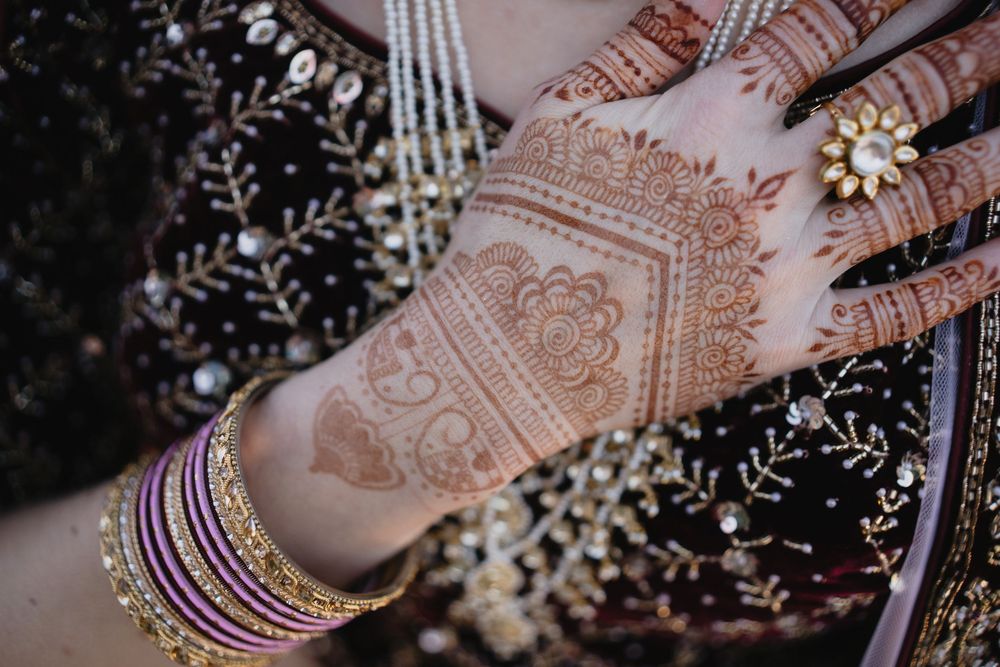 Close-up of intricate bridal mehndi henna design on bride's hand with gold bangles.at Sandia Resort and Casino