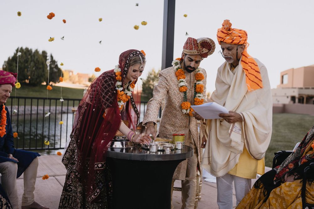 Bride and groom perform Hindu wedding ritual at decorated altar with officiant reading from scripture.at Sandia Resort and Casino
