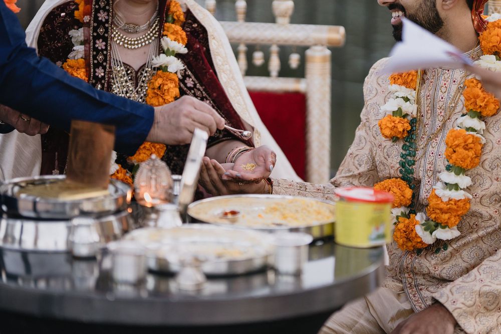Close-up of bride and groom performing traditional Hindu wedding fire ritual with ceremonial offerings.at Sandia Resort and Casino