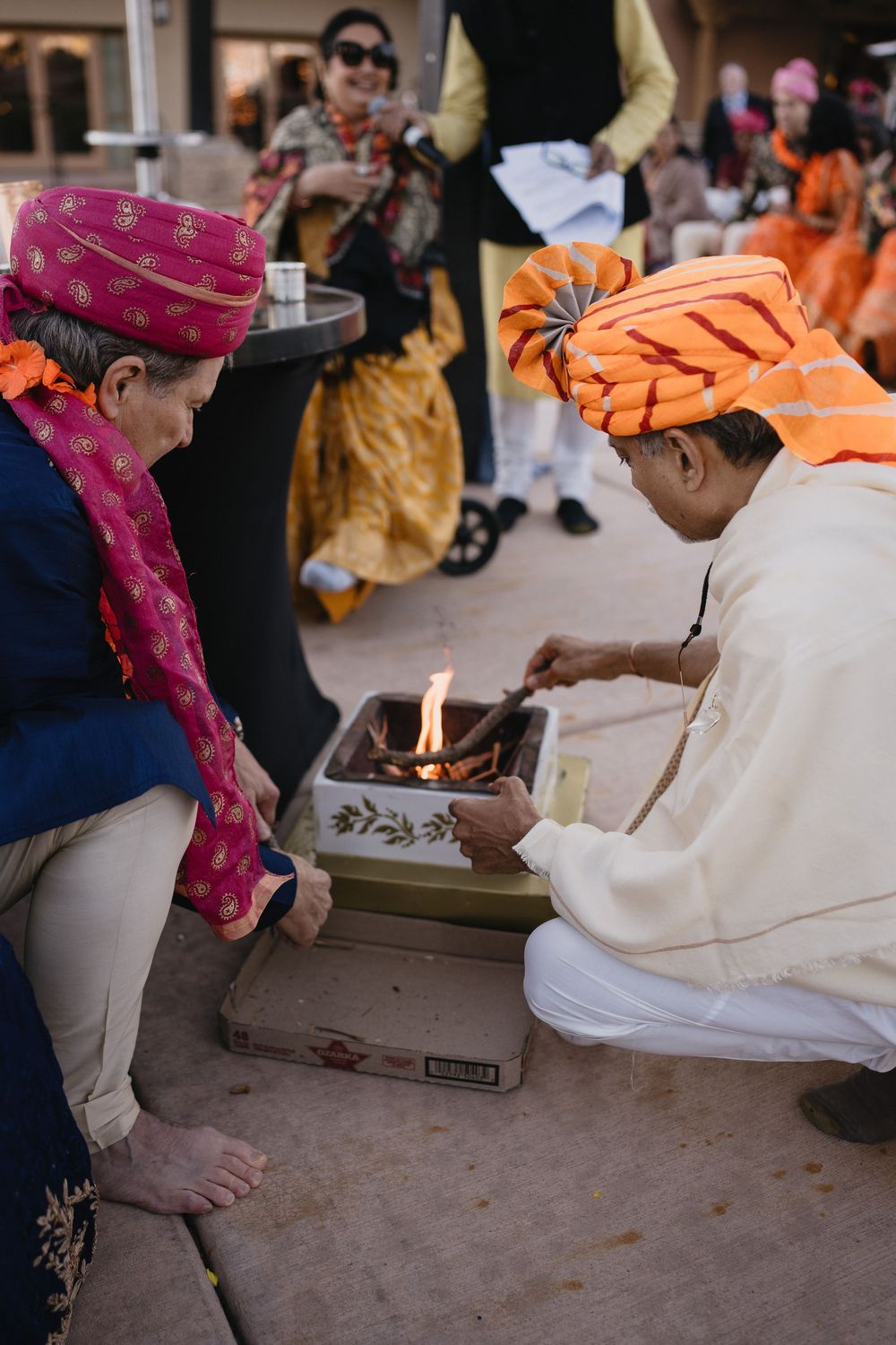 Two men in colorful turbans tending to sacred ceremonial fire during Hindu wedding ritual.at Sandia Resort and Casino
