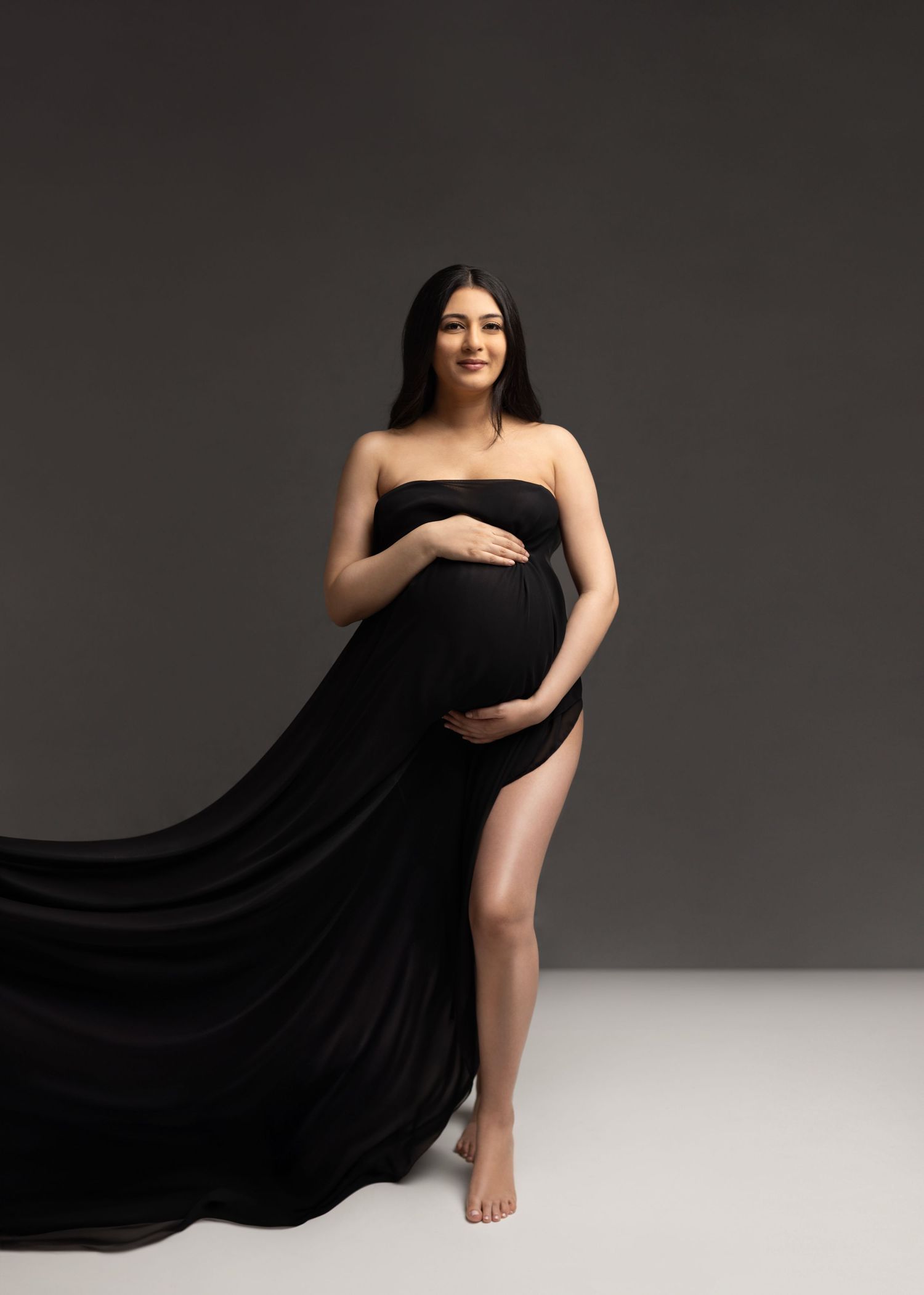 Artistic maternity photo series in black fabric against grey background showing flowing movement and graceful poses.