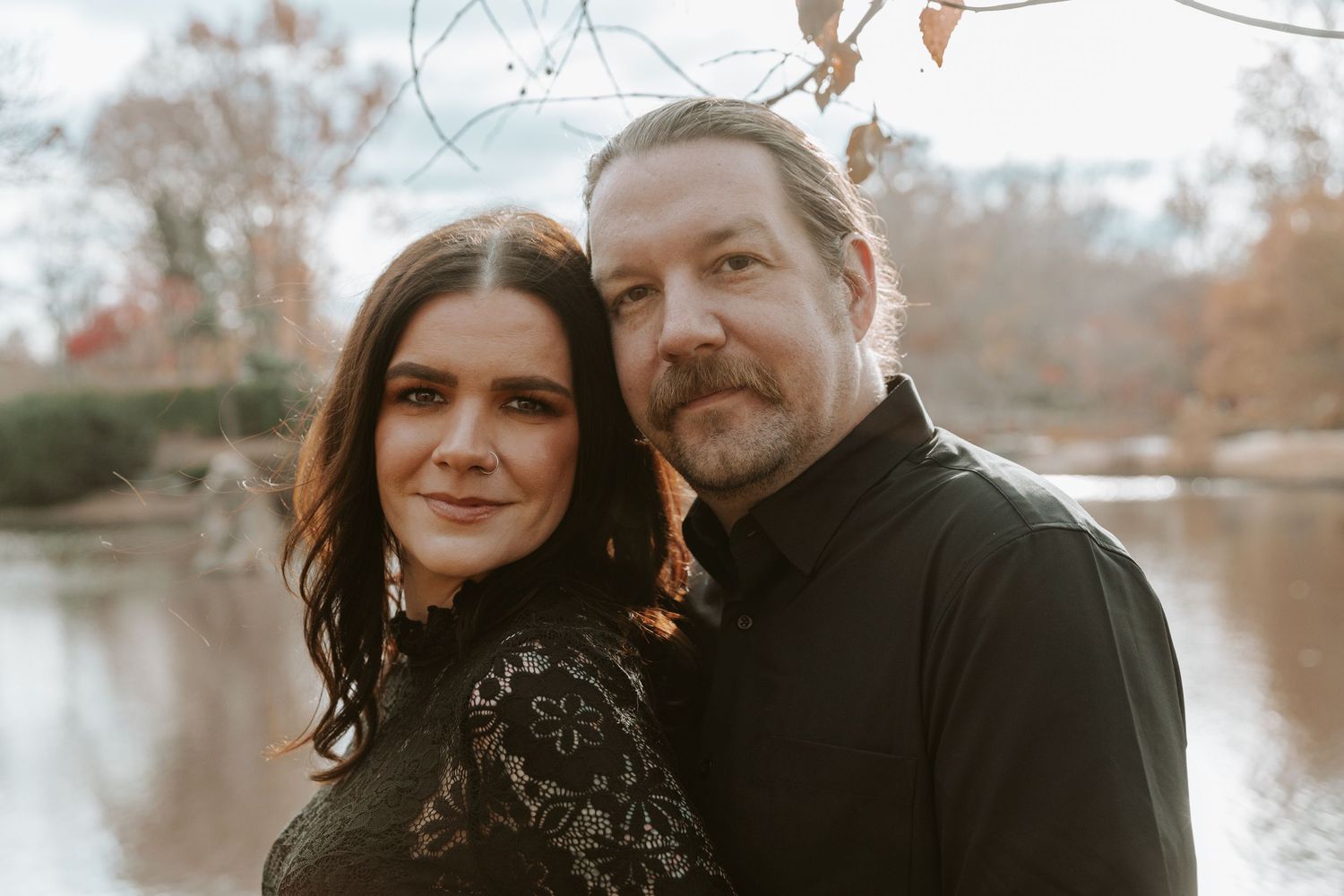 A couple shares an intimate moment together during a fall outdoor photoshoot with autumn foliage in the background. wedding photography st l