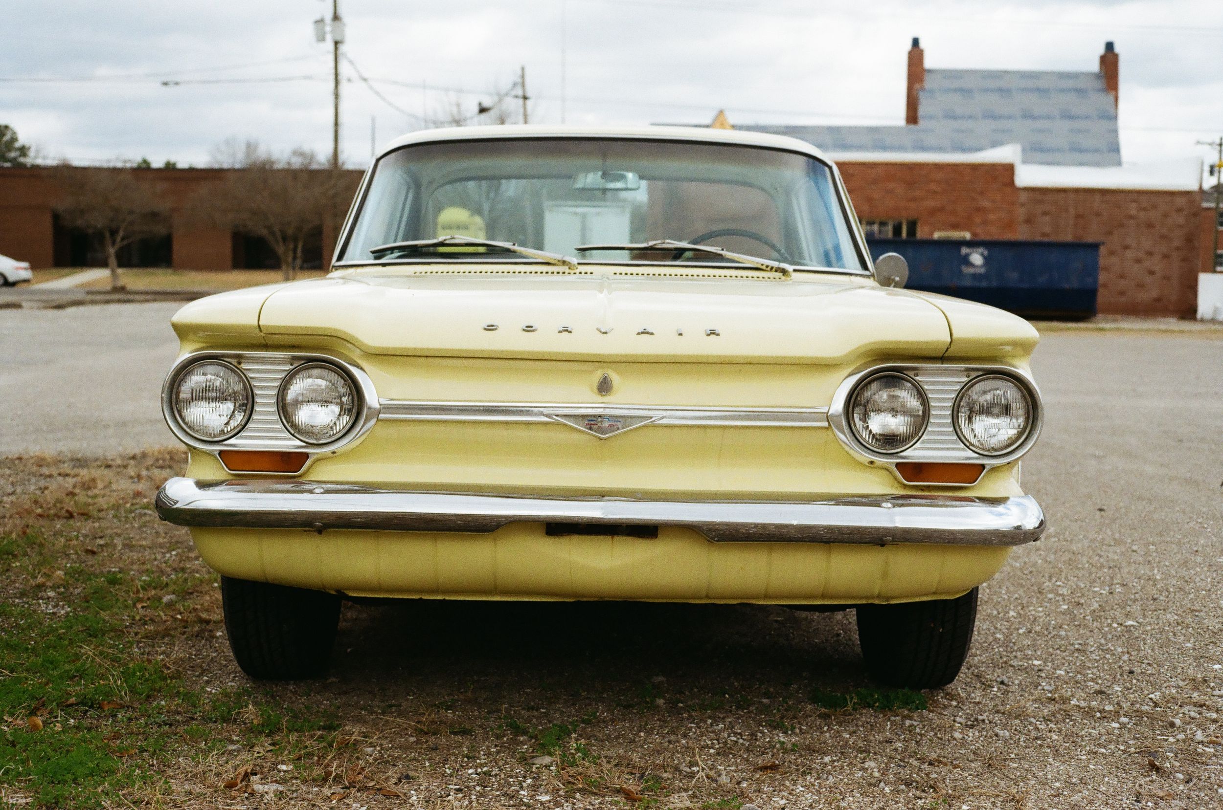 Front view of a vintage gold Chevrolet Corvair showing its distinctive dual headlights and chrome trim details.