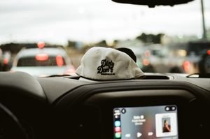 A black truck dashboard with a white vintage style hat that says dirty dans.