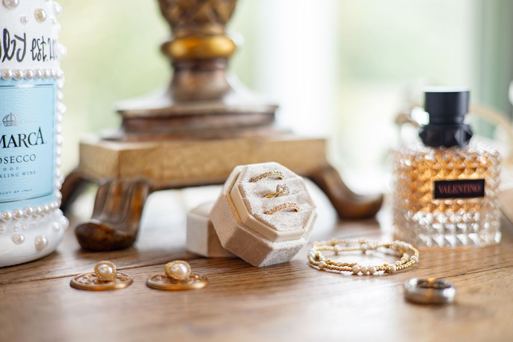 Wedding rings and jewelry details arranged on a wooden surface with soft focus.