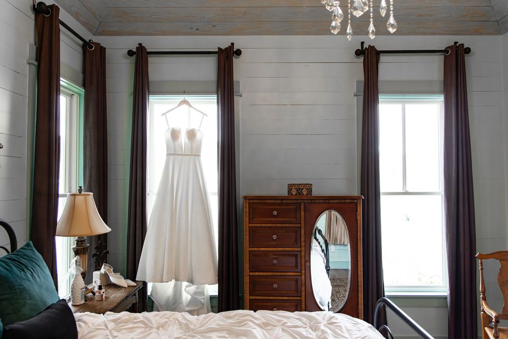 Elegant bridal preparation room with white walls, chandelier, and wedding dress displayed.