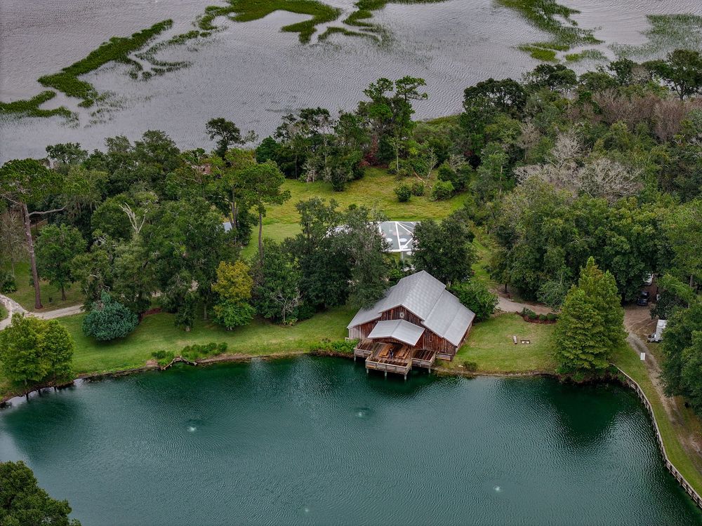 Drone shot of waterfront property with docks and buildings nestled among trees.