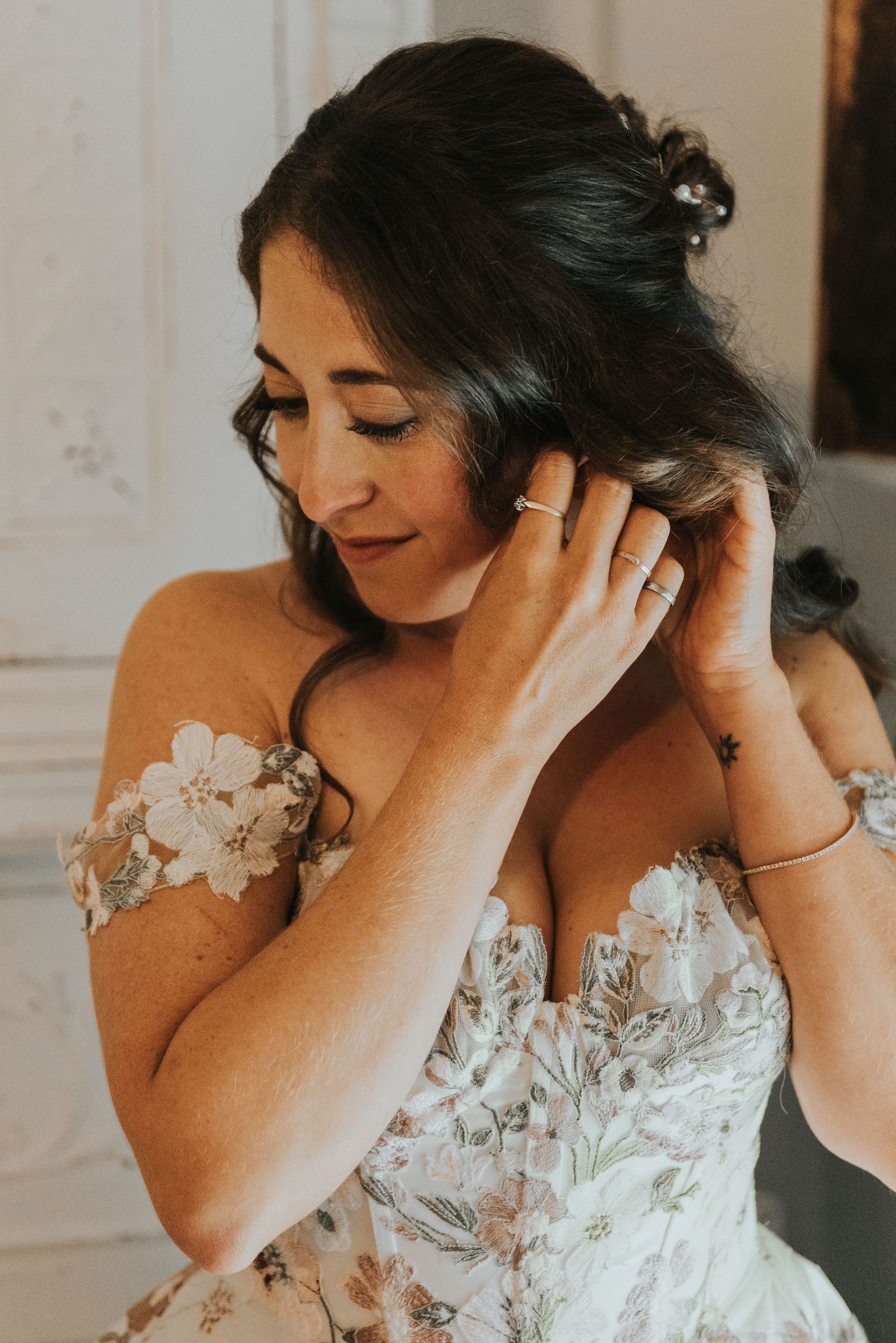 A series of photos showing a bride adjusting her hair while wearing a delicate floral lace wedding dress.