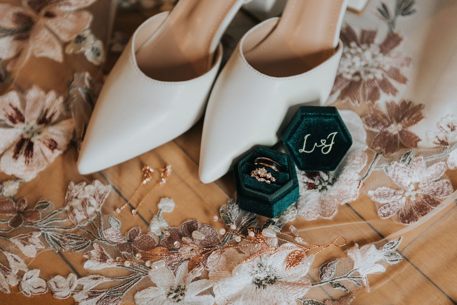 Wedding details including elegant shoes, rings, and delicate lace decorations arranged on a light surface.