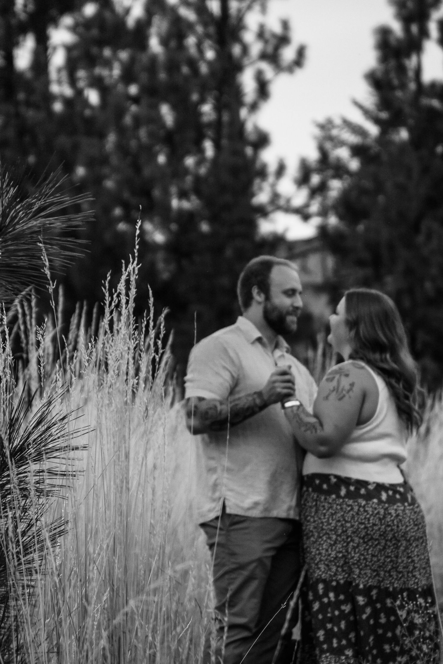 A romantic black and white portrait among tall ornamental grasses at dusk.