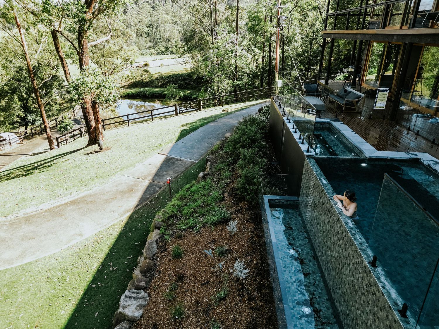 Luxury outdoor infinity pool with stone walls surrounded by lush greenery and trees at a resort retreat.