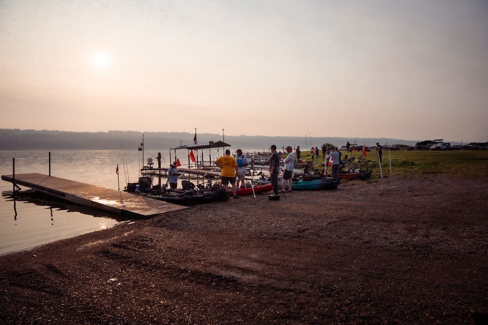 Silhouetted boats line the misty shoreline at sunset creating a serene coastal atmosphere.