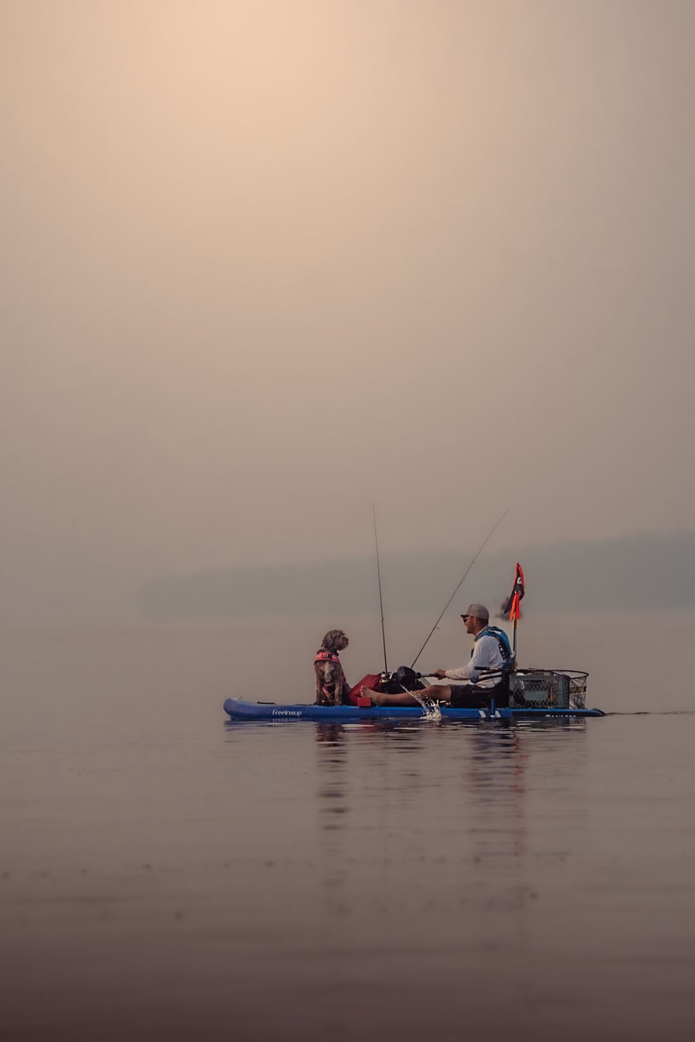 Kayakers paddle through misty waters on a foggy morning, creating a serene and atmospheric scene.