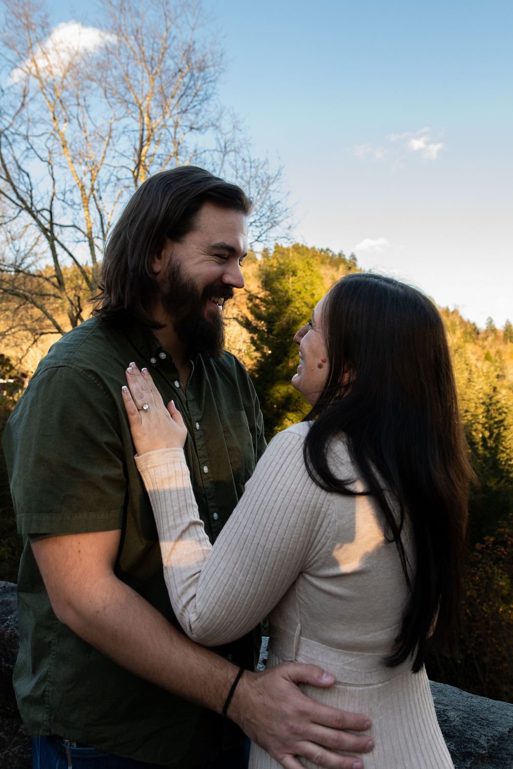 Couple sharing an intimate moment during sunset in a mountain overlook setting.