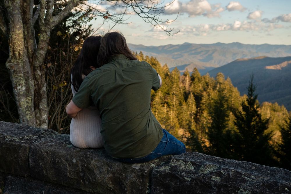 A scenic mountain landscape with golden sunlight illuminating trees and rocky terrain during sunset.